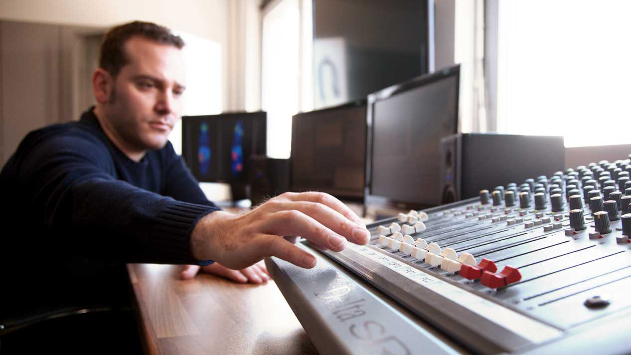 Postproduction employee works with a soundboard in the editing studio