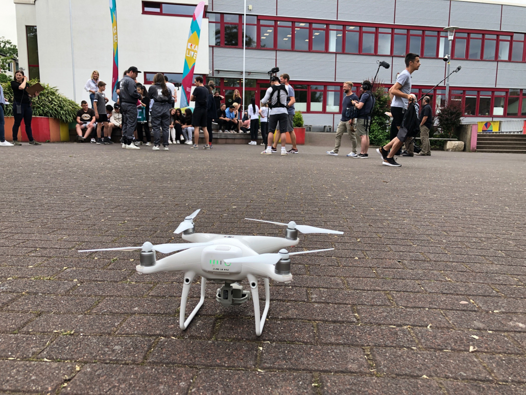 Drohne auf dem Boden und unser Kamerateam auf einem Schulgelände